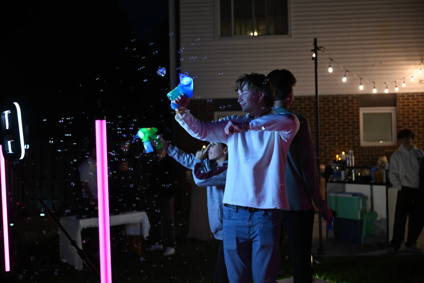 Guests celebrating outdoors with bubbles, props and the AACT booth lighting
